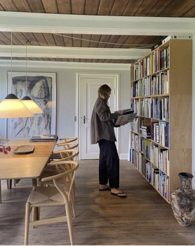 Quiet interior with a woman at a bookshelf